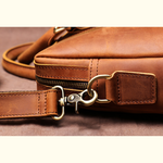 Close-up of a brown leather bag with a gold zipper pull on a matching brown background.